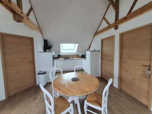 une salle à manger avec une table en bois et des chaises blanches dans l'établissement Gîte au cœur de la campagne, à Saint-Gilles