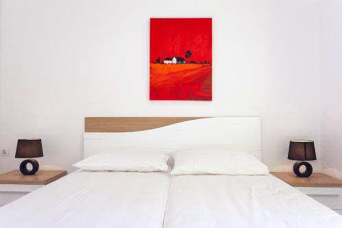 a bedroom with a white bed with two lamps at Apartment Red Coral in Dubrovnik
