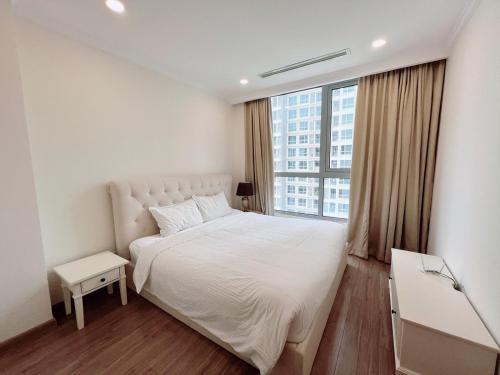 a bedroom with a white bed and a large window at Liam Service Apartment - Vinhome Central Park in Ho Chi Minh City