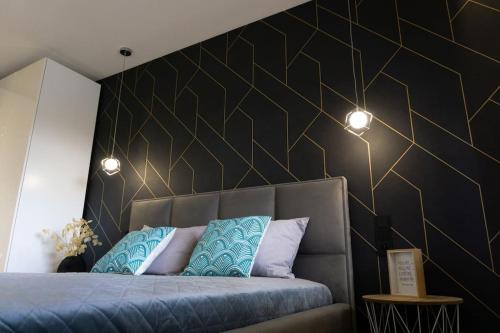 a bedroom with a bed with a black and gold wall at Apartament Roztocze in Tomaszów Lubelski