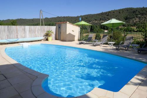 a blue swimming pool with chairs and umbrellas at L'Ecrin du Verdon in Allemagne-en-Provence