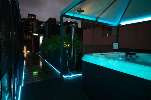 a bathroom with a bath tub on a balcony at night at Hotel NuVe Elements in Singapore