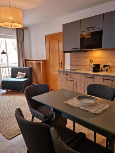 The Lodge at Bad Gastein في باد جاستاين: مطبخ وغرفة معيشة مع طاولة وكراسي