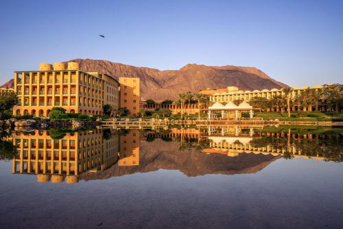 a building with its reflection in a body of water at Strand Beach Resort in Taba