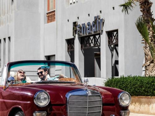 Ein Mann und eine Frau sitzen in einem roten Auto in der Unterkunft Fanadir Hotel El Gouna in Hurghada