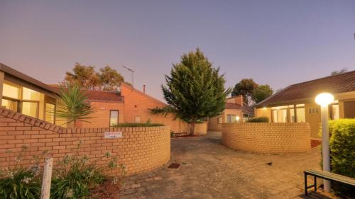 a house with a brick wall and a fence at Executive Hideaway in Benalla