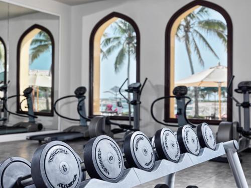 a row of fitness equipment in a gym with palm trees at Juweira Boutique Hotel Adult only in Salalah