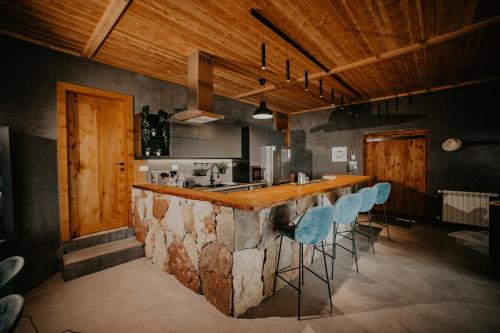 uma cozinha com um grande balcão com bancos de bar azuis em Cedar Scent Guesthouse em Batroûn