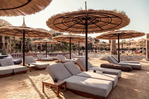 um grupo de cadeiras e guarda-sóis numa praia em Cook’s Club El Gouna (Adults Only) em Hurghada