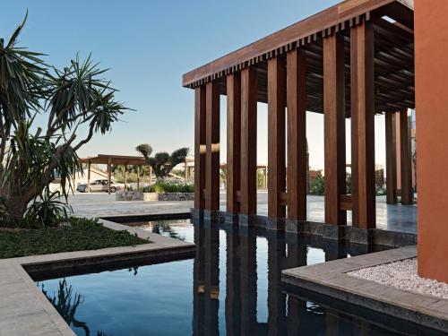 uma piscina de água com um edifício com pilares em The Chedi El Gouna em Hurghada
