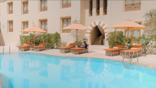 Il propose une grande piscine avec des chaises et des parasols. dans l'établissement Ali Pasha Hotel, à Hurghada