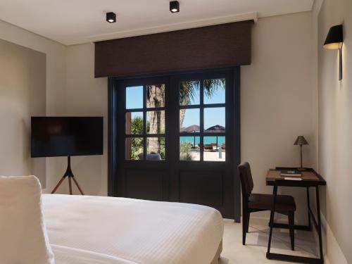 a bedroom with a bed and a desk and a window at The Chedi El Gouna in Hurghada