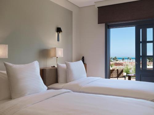 twee bedden in een slaapkamer met uitzicht op de oceaan bij The Chedi El Gouna in Hurghada