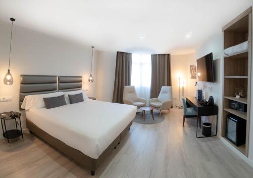 a bedroom with a large white bed and a desk at Hotel Pasarela in Seville