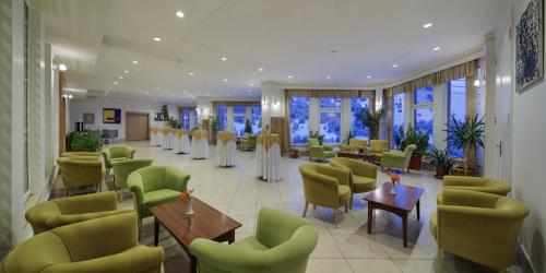 a restaurant with green chairs and tables and windows at Palan Ski & Convention Resort Hotel in Erzurum