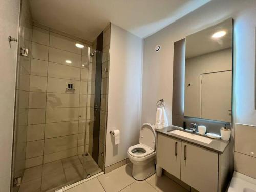 uma casa de banho com um chuveiro, um WC e um lavatório. em Stunning 2 Bedroom Apartment in Rosebank Central em Joanesburgo