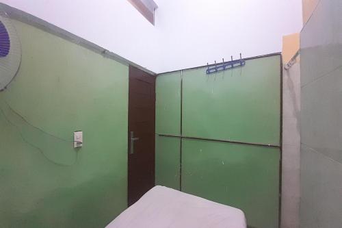 um quarto com portas verdes e uma cama em SPOT ON 92236 Kediri Family Homestay em Medan