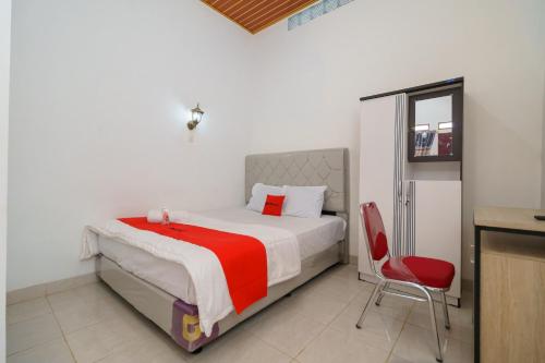 ein Schlafzimmer mit einem Bett und einem roten Stuhl in der Unterkunft RedDoorz @ Jalan Sultan Agung Lampung in Kedaton