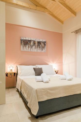 a large bed in a room with a pink wall at Seadrop Suites in Lefkada