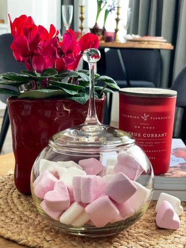 a glass bowl filled with marshmallows in front of a vase of roses at Forest Studio in Druskininkai