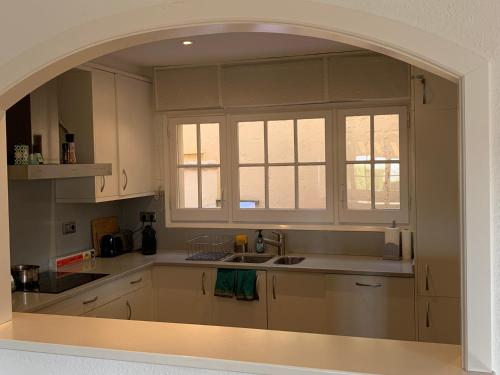 cocina con armarios blancos, fregadero y ventana en Magnifique Villa avec vue mer 8 personnes, en Llafranc