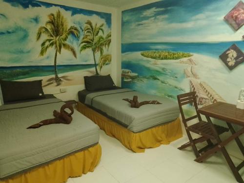 ピピ島にあるReggaeinnの壁に絵画が飾られた部屋のベッド2台