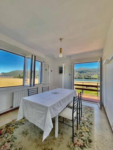 a dining room with a white table and chairs and windows at SAN ANTONIO BEACH by Urdaibai rentals in Busturia