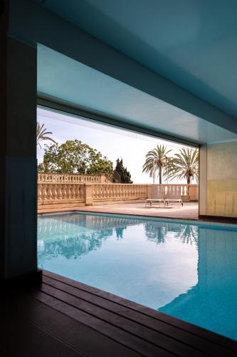 une vue d'une piscine à travers une fenêtre dans l'établissement Le Victoria - Beau 2P avec vue mer, balcon, piscine, sauna et parking privé au centre ville de Menton, à Menton