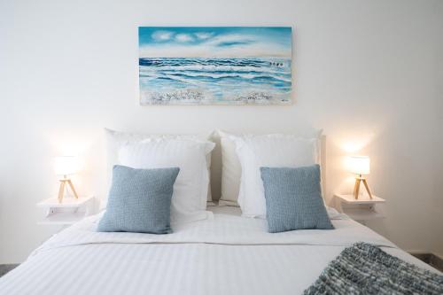 a bedroom with a white bed with blue pillows at Le Victoria - Beau 2P avec vue mer, balcon, piscine, sauna et parking privé au centre ville de Menton in Menton