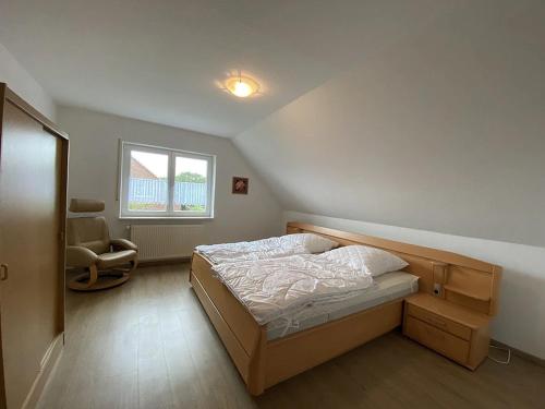a bedroom with a bed and a chair and a window at Ferienwohnung Zur Kuhweide in Dunum