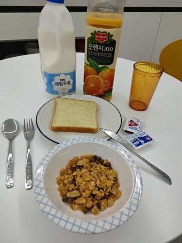 een tafel met een bord granen, brood en melk bij Athene Motel in Gwangju