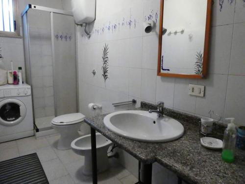 a bathroom with a sink and a toilet and a mirror at Casa Lore al mare in Santa Lucia