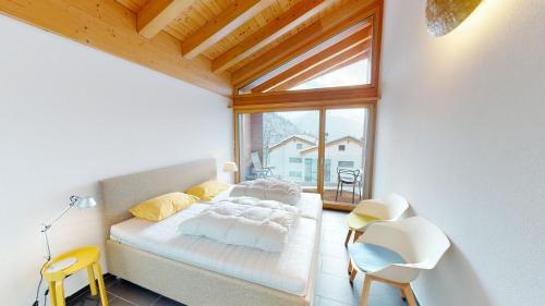 1 dormitorio con cama y ventana grande en Bergquell Haus A, en Blatten bei Naters
