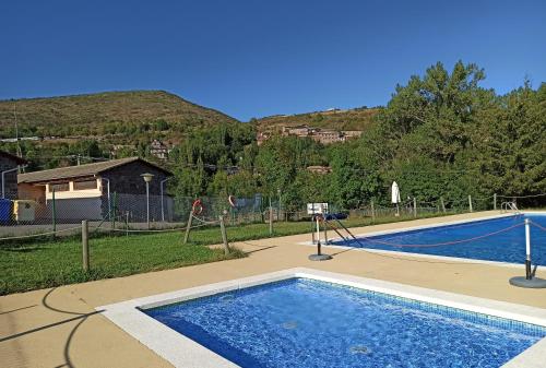 Laspaúles的住宿－Bungalows Laspaúles，一座位于庭院内的游泳池,山丘位于酒店后面