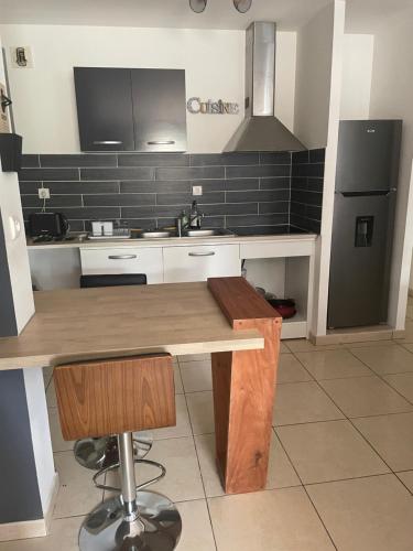 eine Küche mit einem Holztisch und einem schwarzen Kühlschrank in der Unterkunft Appartement t3 rdc in Saint-Denis