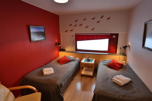 two beds in a room with red walls at Ylläs Lake Hotel in Ylläsjärvi