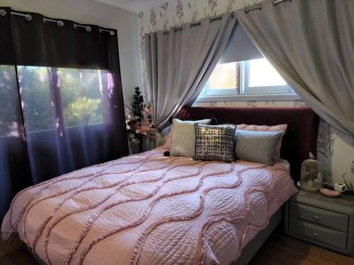 a bedroom with a bed with a pink comforter and windows at Boutique style accomodation near Busselton Jetty in Busselton