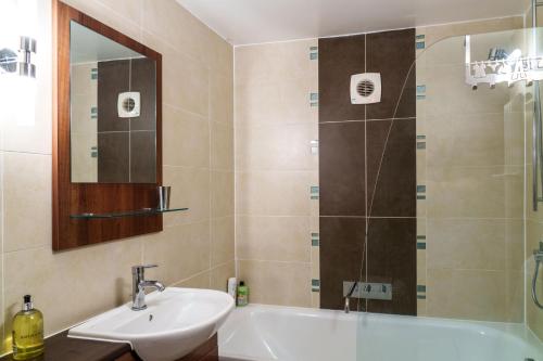 a bathroom with a sink and a tub and a mirror at 12 Ullswater Suite - Whitbarrow Village in Penruddock