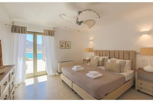 1 dormitorio con cama y ventana grande en Elite Mykonos Villa - Villa Roxane - Private Pool - 6 Bedrooms - Beachfront - Ftelia en Dexamenes