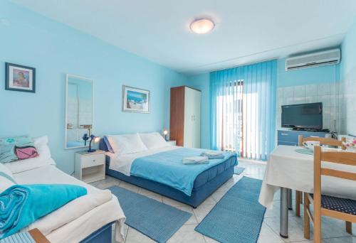 a blue bedroom with two beds and a tv at Savić Biograd in Biograd na Moru