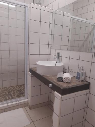 biała łazienka z umywalką i prysznicem w obiekcie Aspasia Agency CC w mieście Mariental