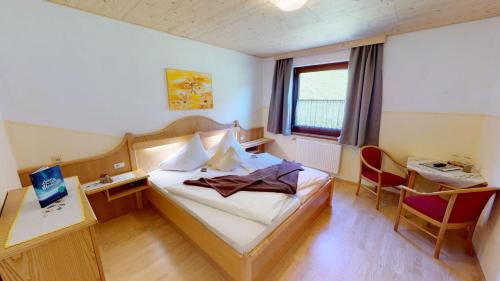 a hotel room with a bed and a desk and a window at Berghotel Presslauer in Jenig