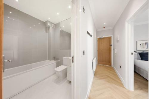 a white bathroom with a tub and a toilet at Pleasing 2bed flat 10min to Wimbledon tennis court in London