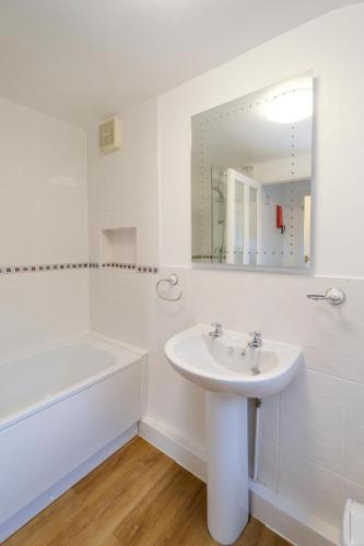 a white bathroom with a sink and a bath tub at 39 Carr Avenue - Aldeburgh Coastal Cottages in Leiston