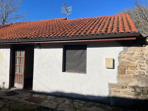 un bâtiment blanc avec un toit rouge et une fenêtre dans l'établissement Casa de Guimarás., 