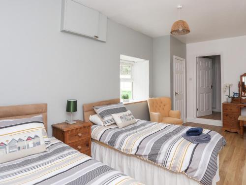 a bedroom with two beds and a chair at 2 The Coach House in Pentraeth