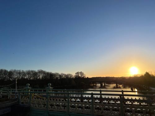 a sunset over a fence and a river at Gorgeous 1 bed flat near Richmond Bridge. in Richmond