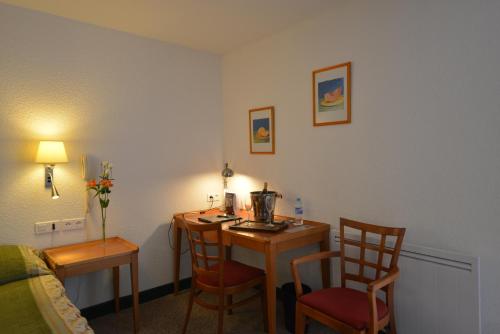 a room with a desk and two chairs and a table at Hotel Bomotel in Montluçon