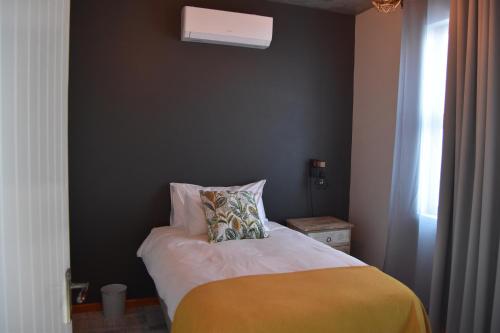a bedroom with a bed with a pillow and a window at Quiver Inn Guesthouse in Keetmanshoop