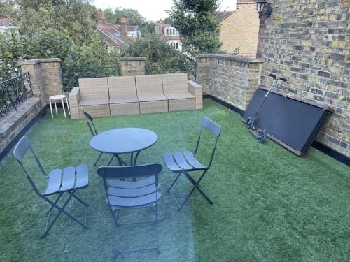 un patio con mesa y sillas en el césped en Spacious two bedroom flat in prestigious Highgate. en Londres